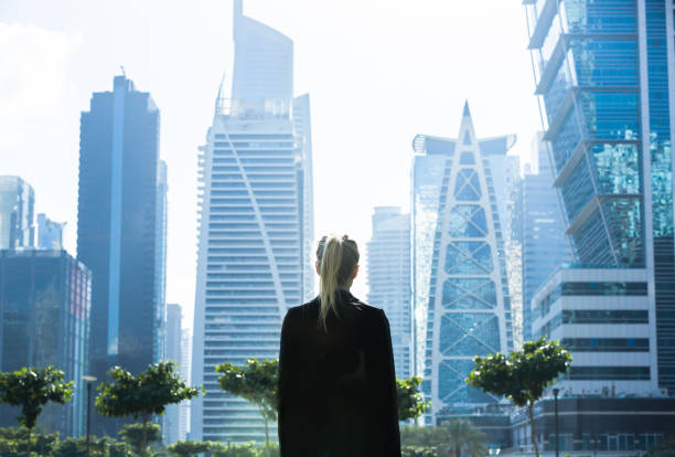 A businesswoman stands in front of modern skyscrapers, symbolizing the potential of establishing a company in KIZAD Free Zone.