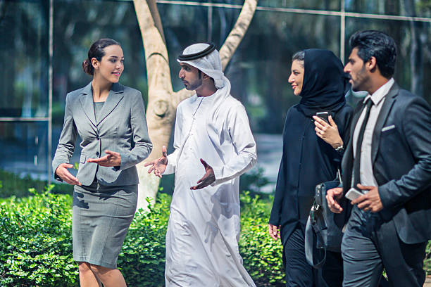 A group of diverse business professionals discuss opportunities at KIZAD Free Zone outdoors.